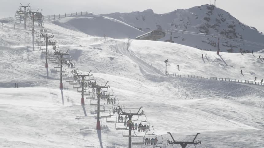 People riding a ski lift up a snowy mountain