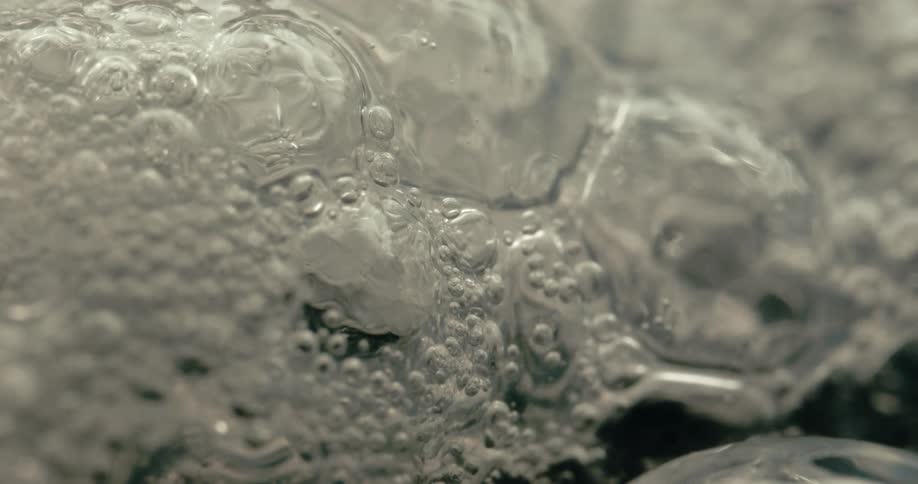Air bubbles collect on a liquid surface seen in closeup