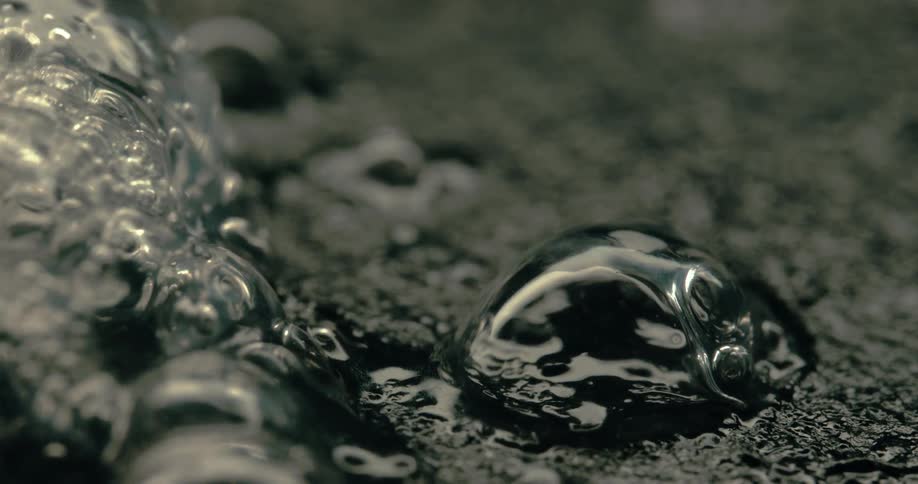 Closeup of dark glistening bubbles forming in a viscous liquid on a textured surface