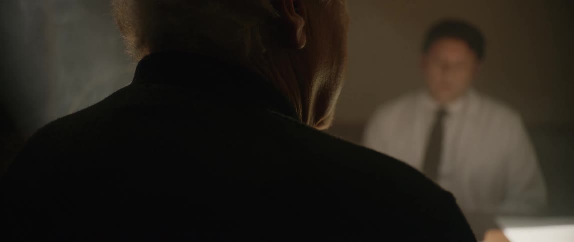 Two people sitting at a table in a room are talking