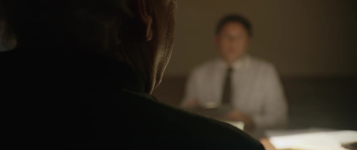 Two people sitting at a table in a lowlight environment are talking