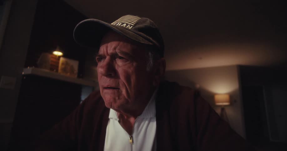 Elderly man in cap interacting with laptop and getting happy