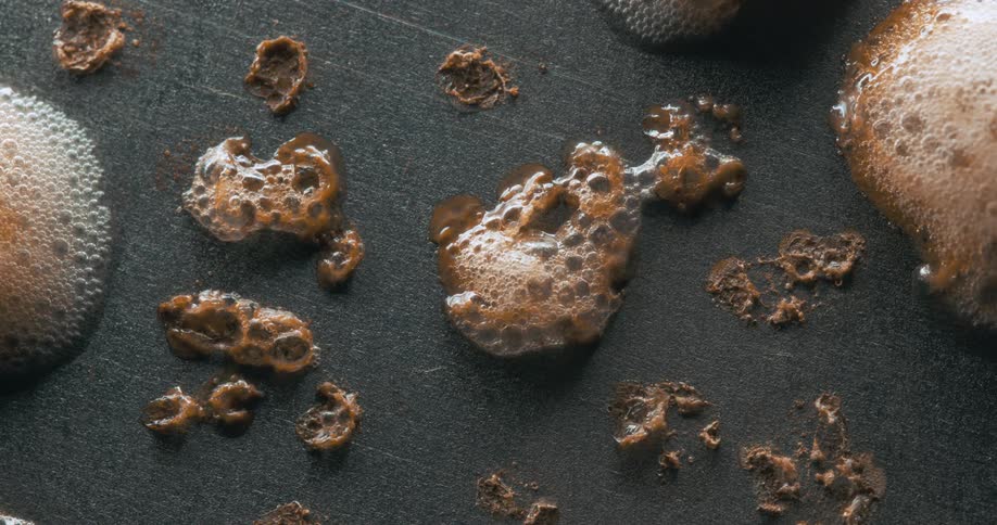 Brown liquid bubbling and foaming on a grey surface