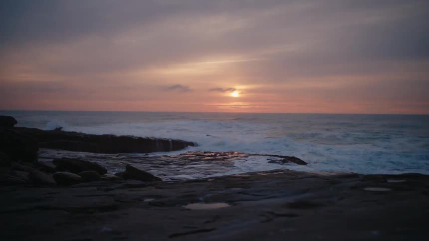 The sun sets on the rough shore water