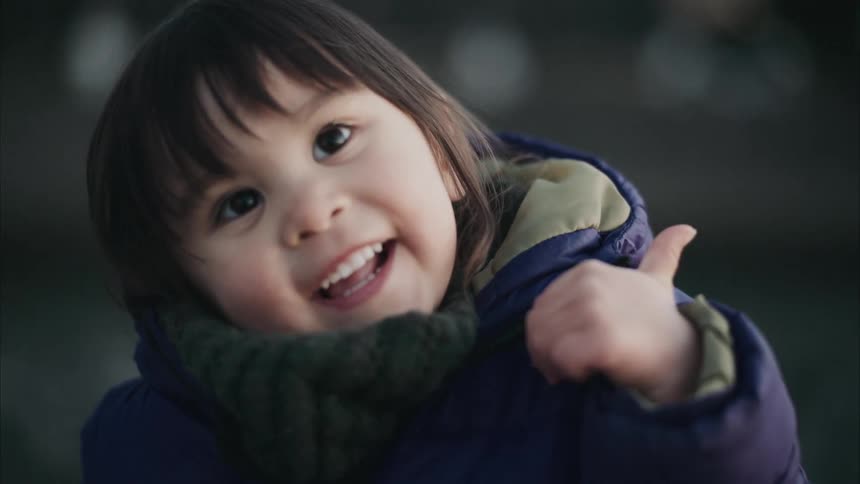 A child smiles while giving a thumbs up