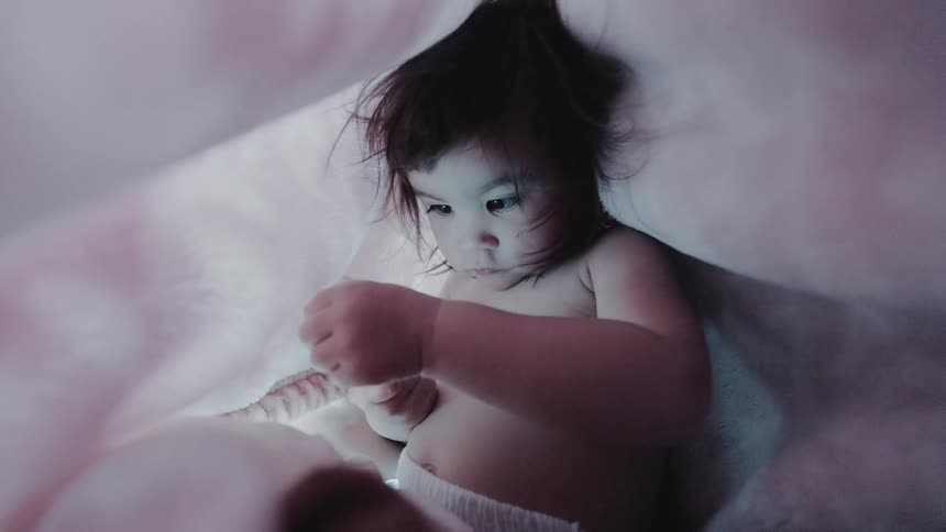 Little girl under a blanket playing with her teddy bear