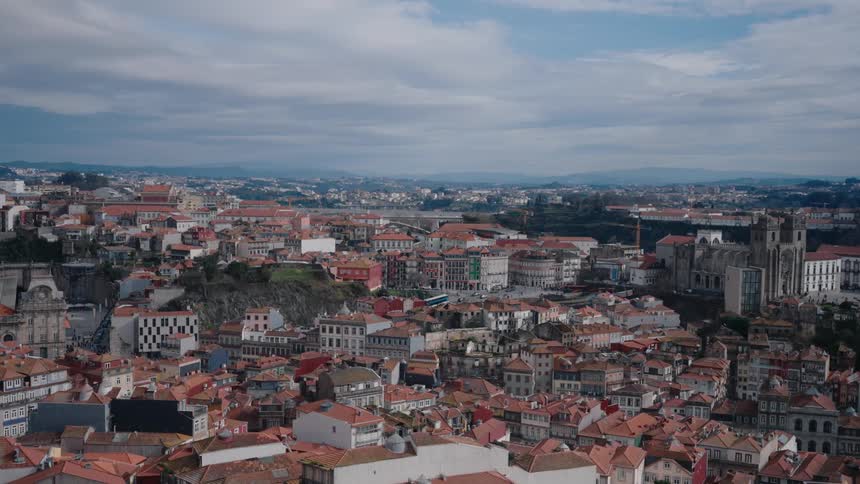 Landmark buildings tower over the surrounding red roofed buildings in hilly terrain on a cloudy day
