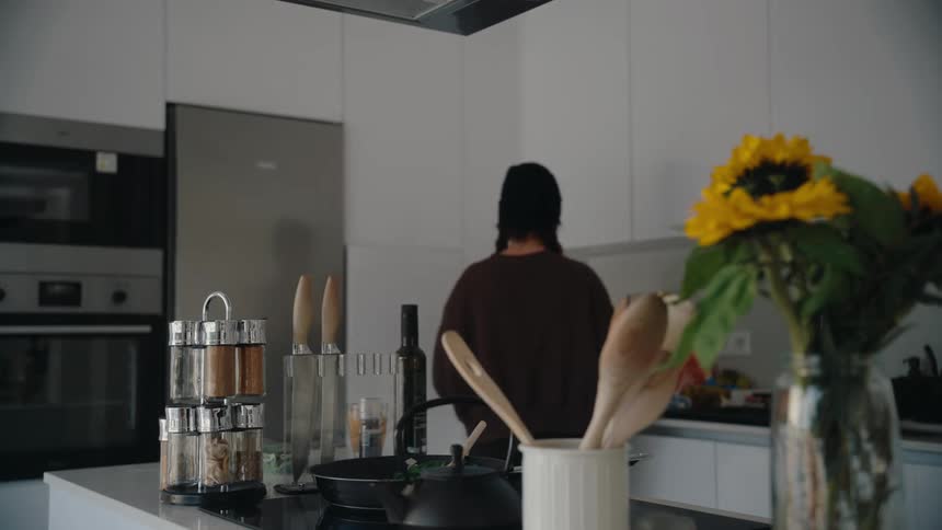 A woman puts spices in the pan