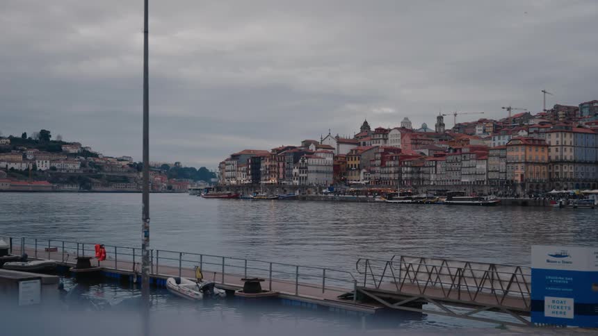 Walkway leads across the water a distance from the apartment buildings standing near the docks under and overcast sky