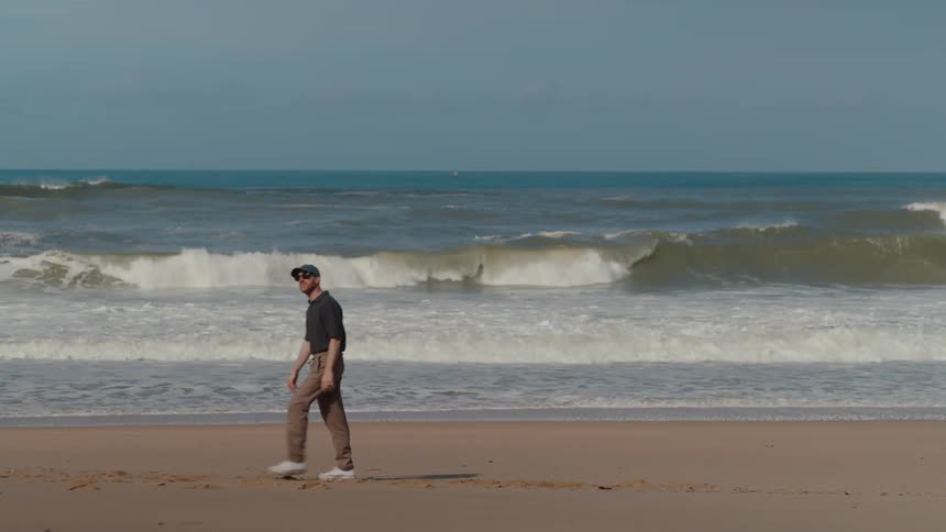 Man walks along the side of the ocean coast
