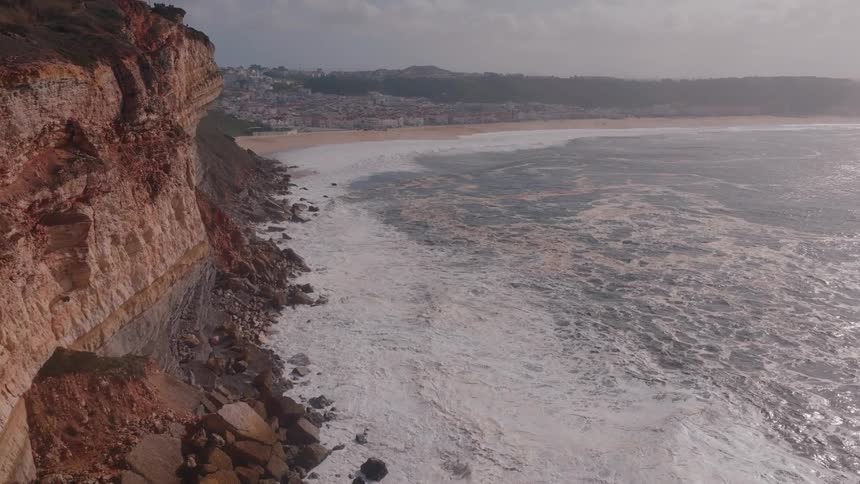 Coastal scenery of a rough sea and a city in the background