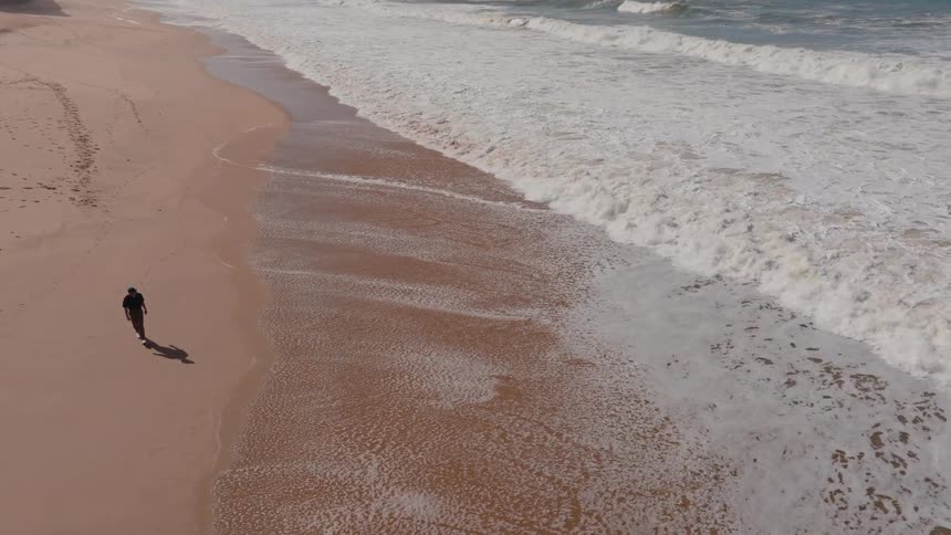 Man walking along the edge of a beach