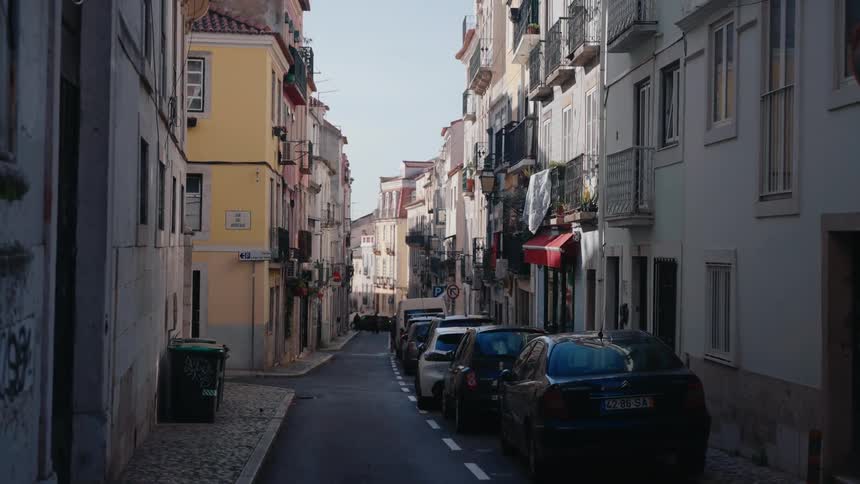 Narrow street of a city with classic buildings and parked vehicles