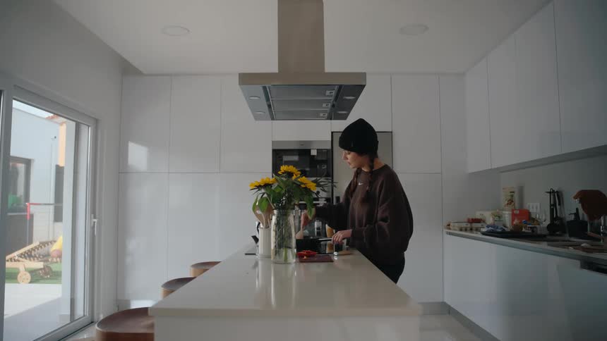 Woman stirs food in a pot while cooking in her kitchen during the daytime