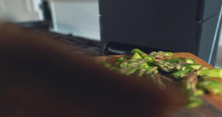 A chef in the kitchen placing sliced asparagus into an air fryer