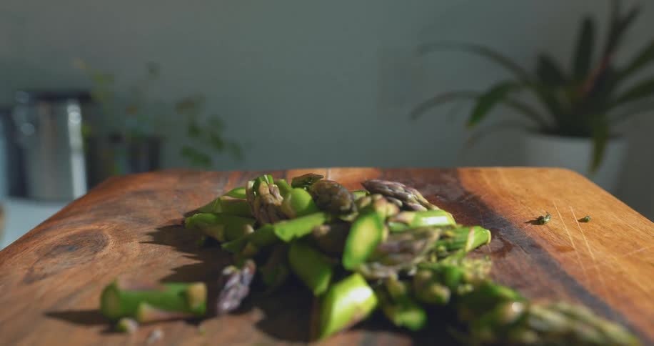 Freshly cut asparagus is arranged on a wooden board