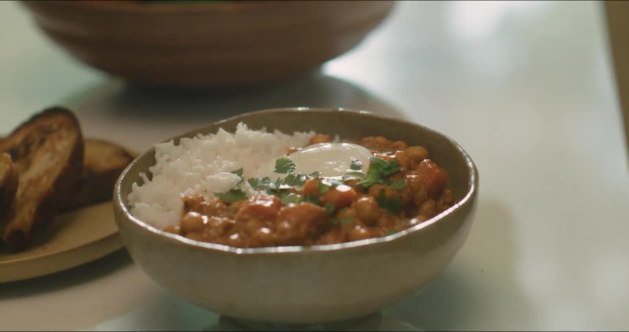 A bowl of rice and beans is on a table next to a plate of toasted bread