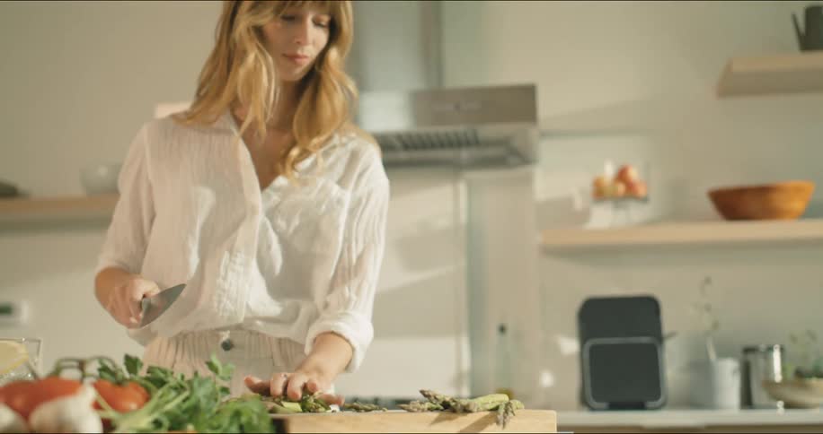 A woman is cutting vegetables in her kitchen