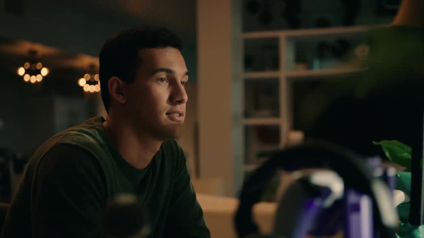 A man is talking as he looks at a laptop