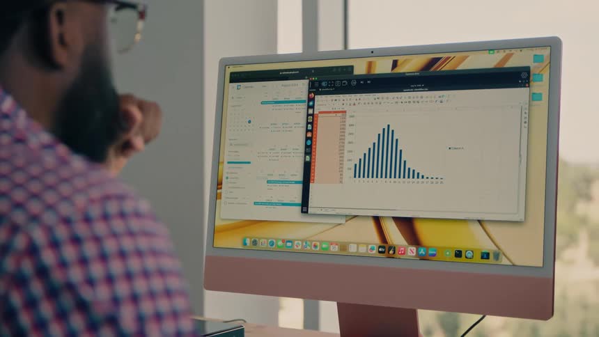 Man consults a graph on a large screen while working in an office