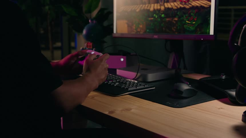 Gamer plays a computer game using a game controller while sitting at a desk