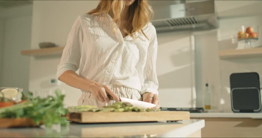 A woman is cutting vegetables in the kitchen
