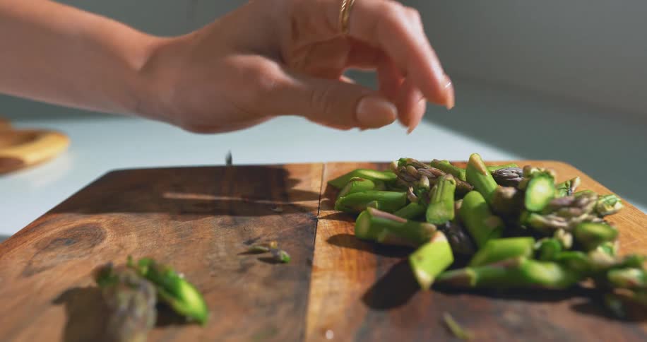 Woman picks through pieces of asparagus lying on a chopping board