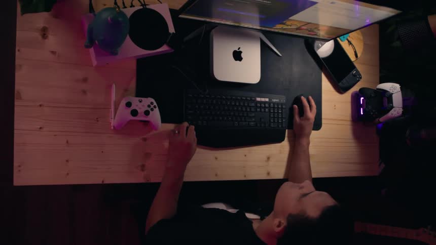 A man sits at a desk deeply focused on a computer screen in a dimly lit tech savvy setting with an artistic orbiting camera angle
