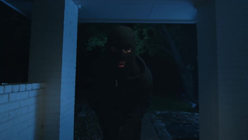 Hooded thief sneaking into a house