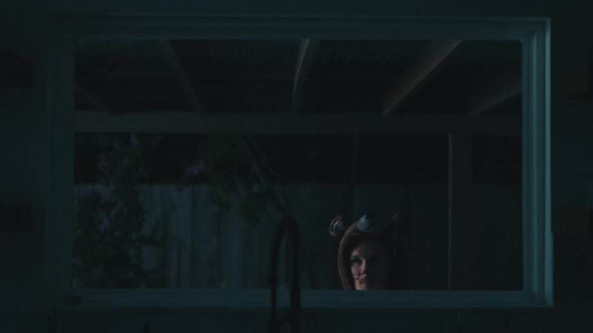 Man in a costume walking carefully next to a mirror in a house at night