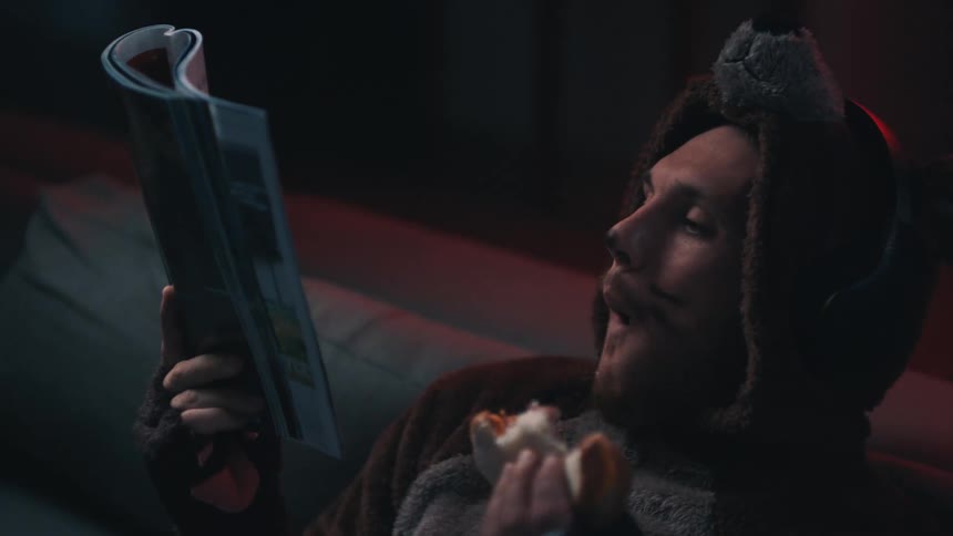 Person sitting on sofa reading magazine putting hands up with police siren flashing