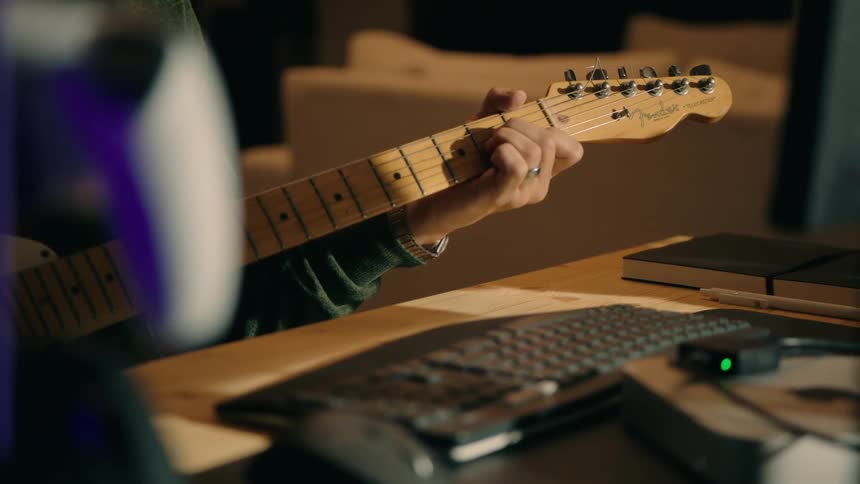 A person is playing the guitar at his desk