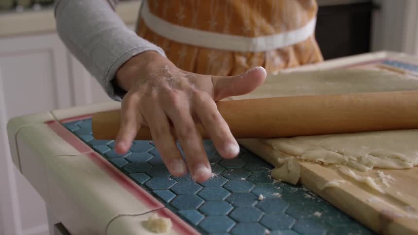 A woman rolls out dough with a rolling pin