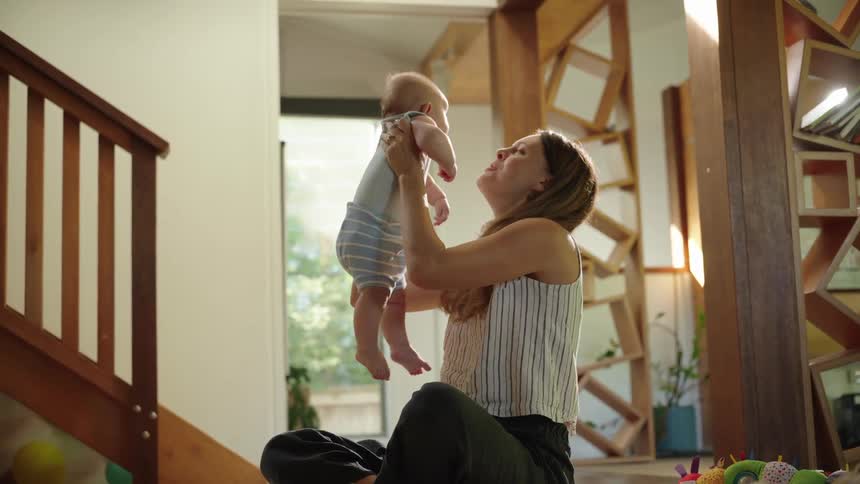 Mother sitting holding her daughter drinking and playing