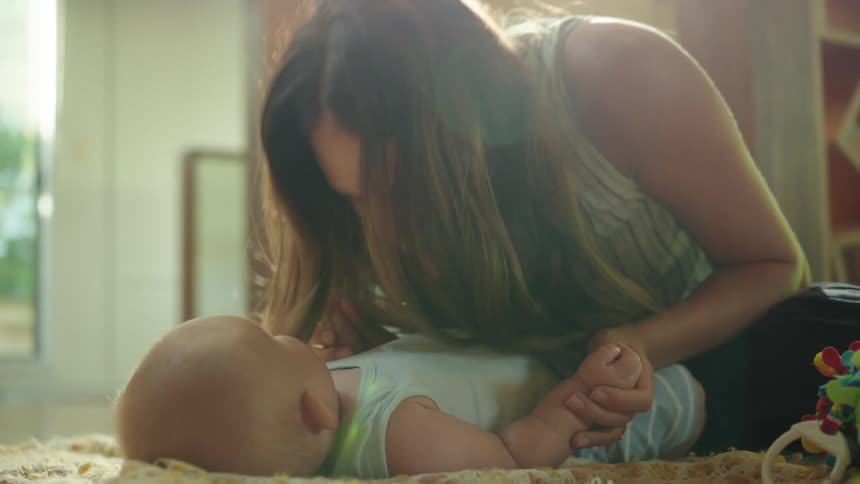 A mother playing with her baby kisses him on the belly