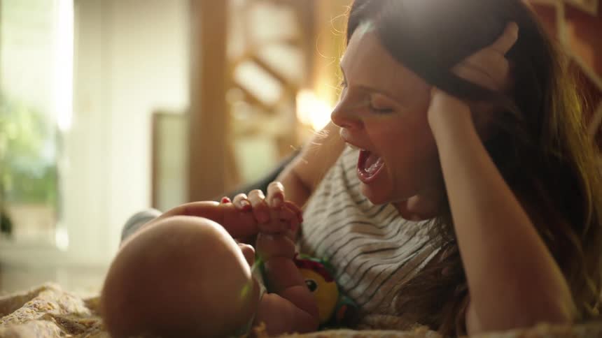 Mother kisses and plays with her baby