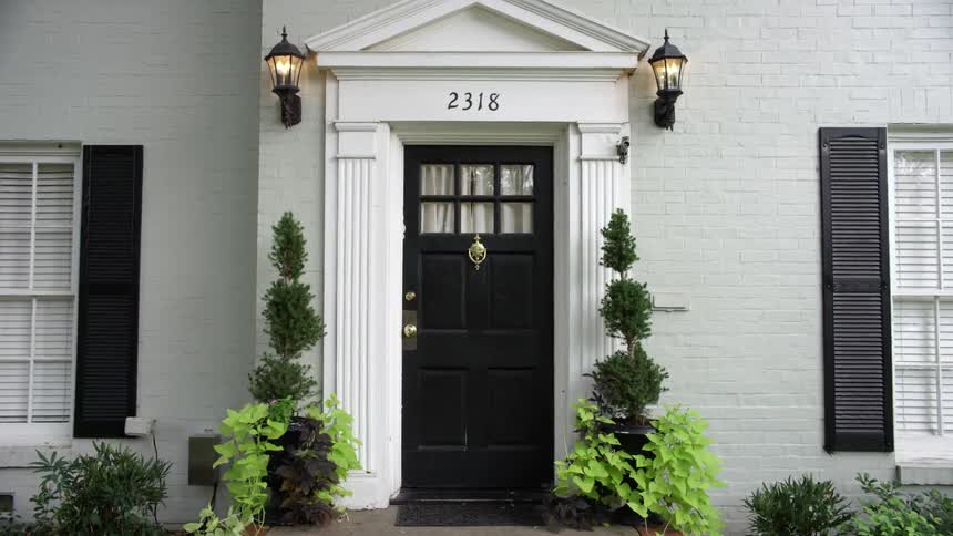 Two sconces are lit outside a black front door