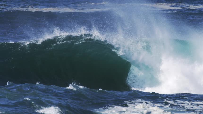 Heavy waves cause the ocean water to rise splashing through with aggression at midday