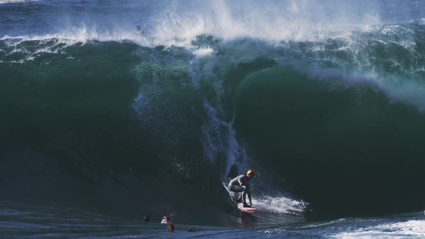 Surfers in the ocean with one of them riding a tubular wave