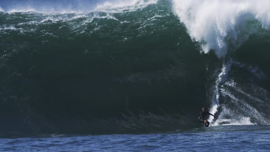 A surfer is riding a massive wave in the ocean