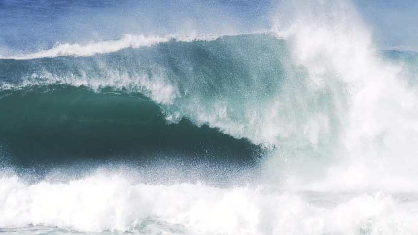 Heavy waves cause the ocean water to rise splashing through with aggression at midday