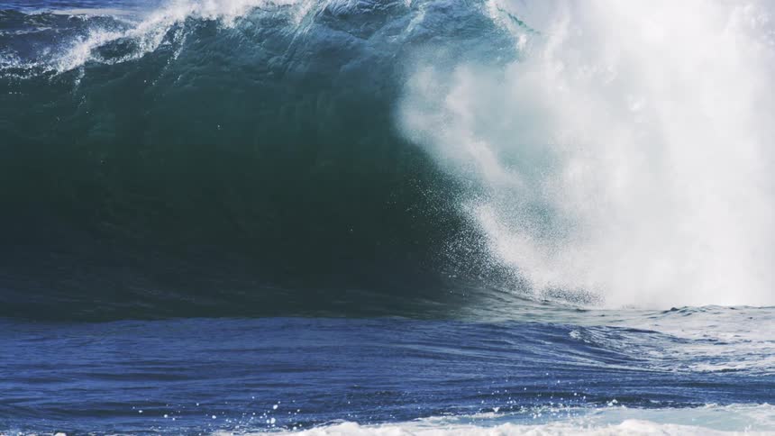 Heavy waves cause the ocean water to rise splashing through with aggression at midday