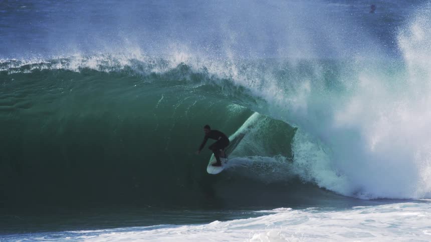 A surfer rides inside the barrel of a large wave in an intense ocean moment