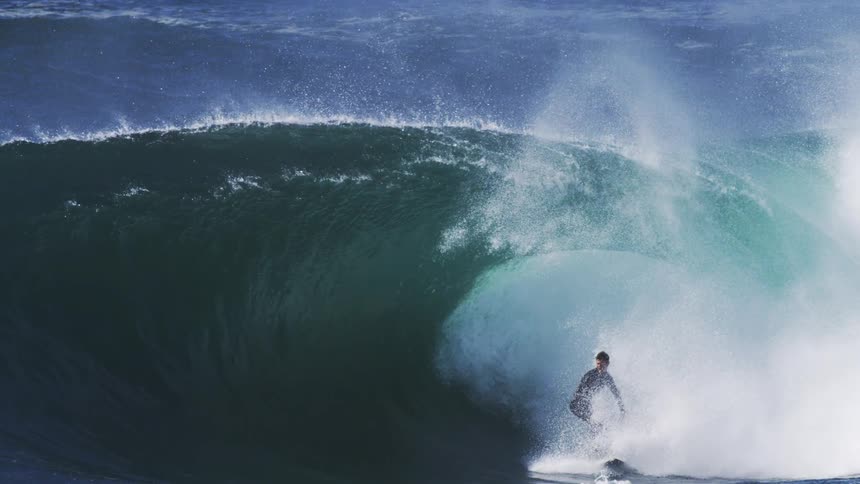 A man surfs a tubular wave on a sunny day