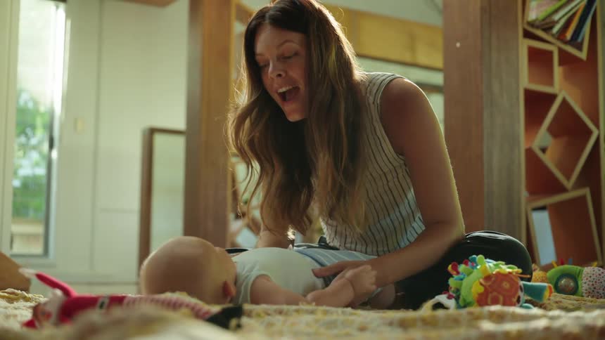 Woman playing with a baby lying on the carpet