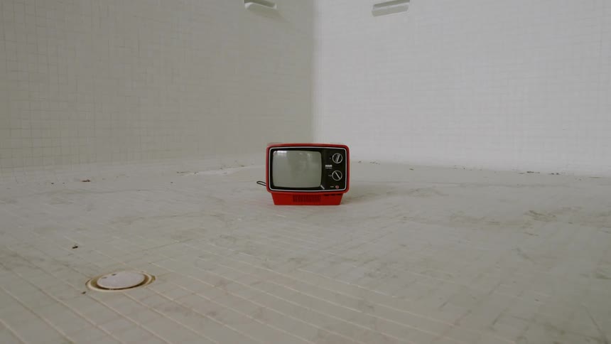 A small, red tv is sitting in an empty pool