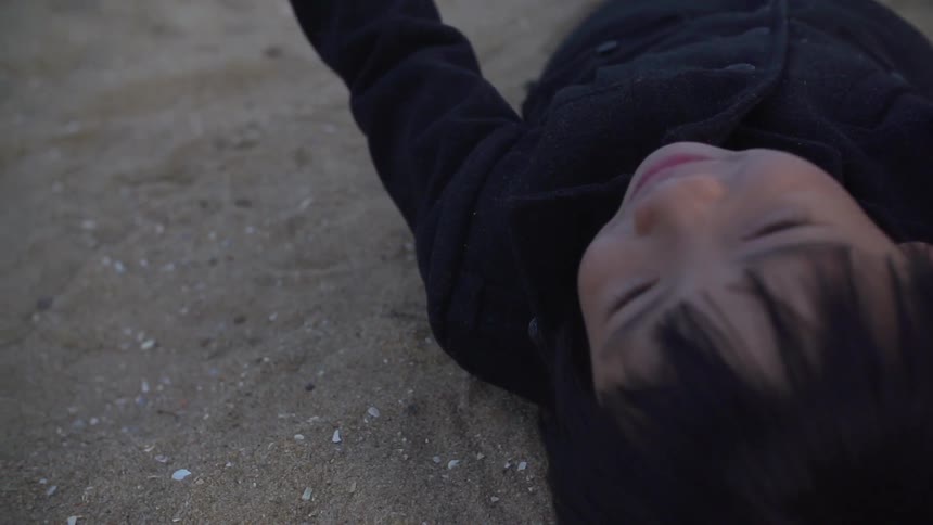 A kid rolling around in the sand