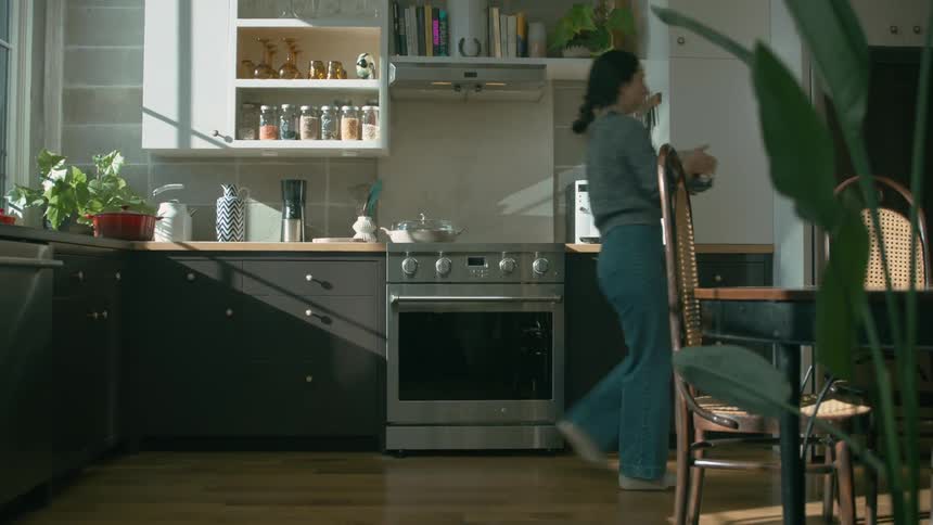 A woman taking food from the counter top and placing it in the fridge