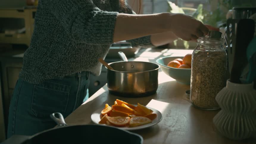 A woman pours ingredients into a pot and stirs