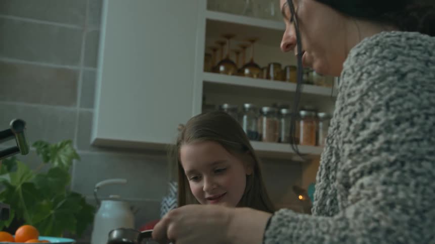 Little daughter helping her mother cook